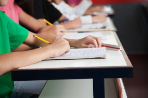 High School Students Writing On Paper At Desk